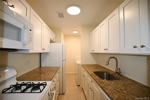 a kitchen with granite countertop a stove sink and cabinets