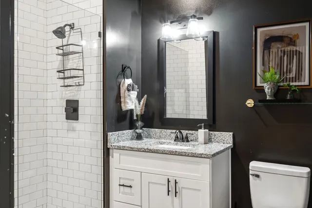 a bathroom with a granite countertop sink a toilet and shower
