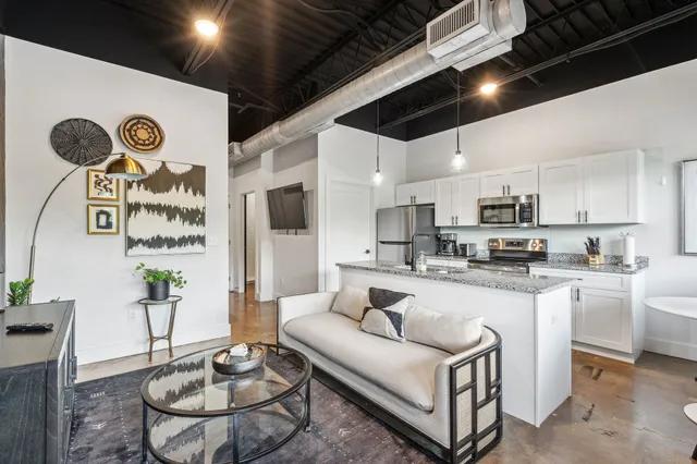 a living room with stainless steel appliances kitchen island a table and chairs in it