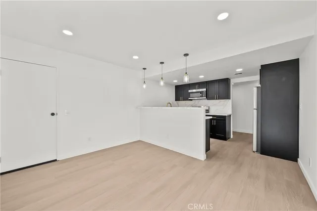 a view of a kitchen with kitchen island stainless steel appliances wooden floor sink and a window