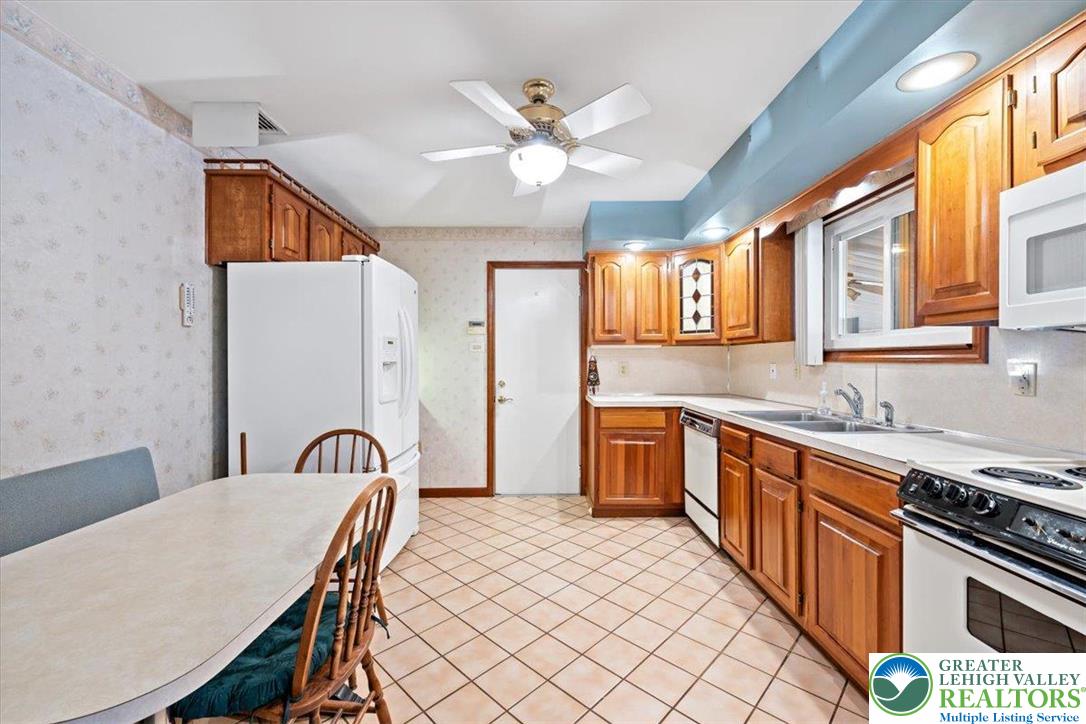 1240 Ridge Avenue Whitehall, PA 18052 - Photo 15 of 52 a kitchen with stainless steel appliances granite countertop a sink dishwasher a stove a refrigerator with a dining table and chairs with wooden floor