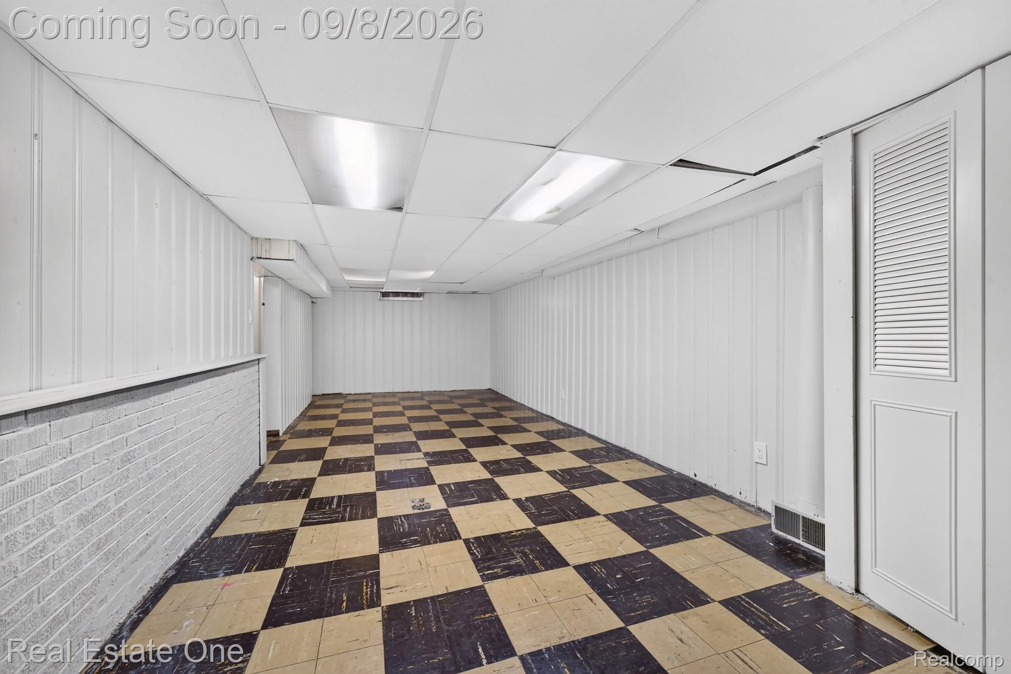 7961 Merrick Street Taylor, MI 48180 - Photo 29 of 39 Spacious room featuring checkered flooring, white paneling, white brick accent, and a drop ceiling with recessed lighting