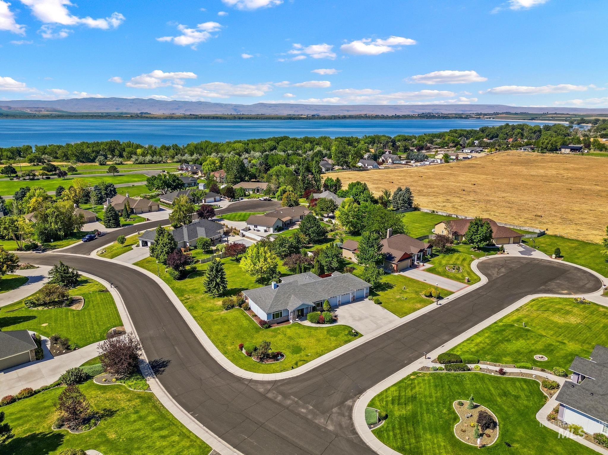 15181 Drury Way Caldwell, ID 83607 - Photo 3 of 49 Residential neighborhood featuring mature landscaping, paved streets, and a waterfront setting with distant mountains