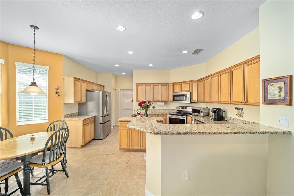 7947 South W 83rd Place Ocala, FL 34476 - Photo 21 of 28 a kitchen with stainless steel appliances granite countertop a sink a stove a refrigerator a dining table and chairs with wooden floor