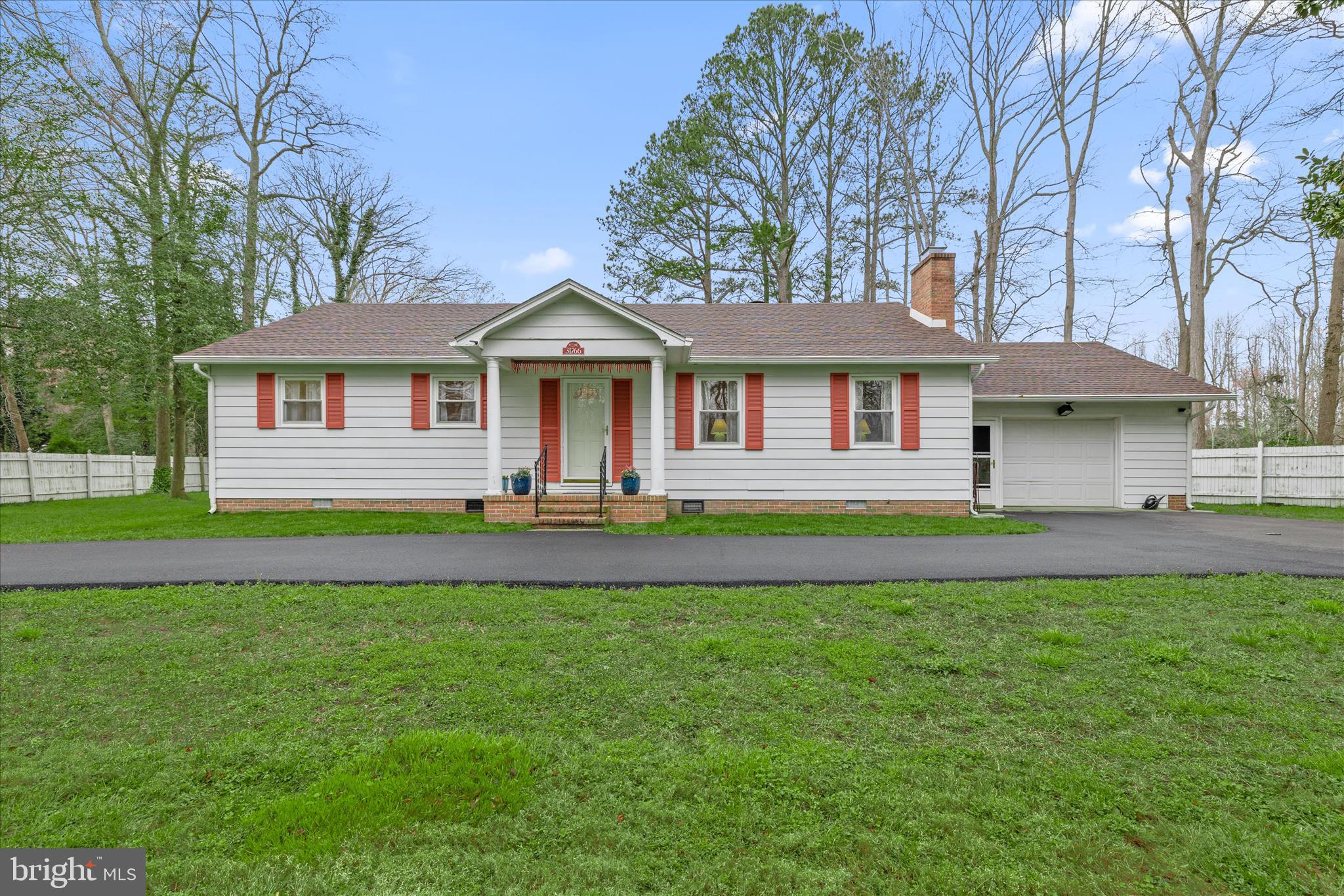 a front view of a house with a garden and trees