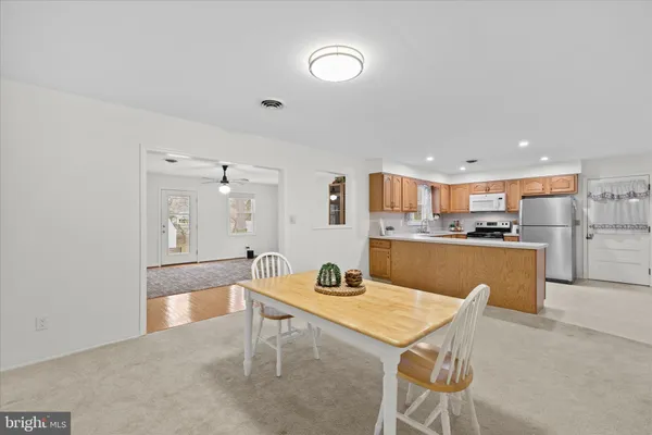 a room with stainless steel appliances kitchen island granite countertop a sink a stove a dining table and chairs