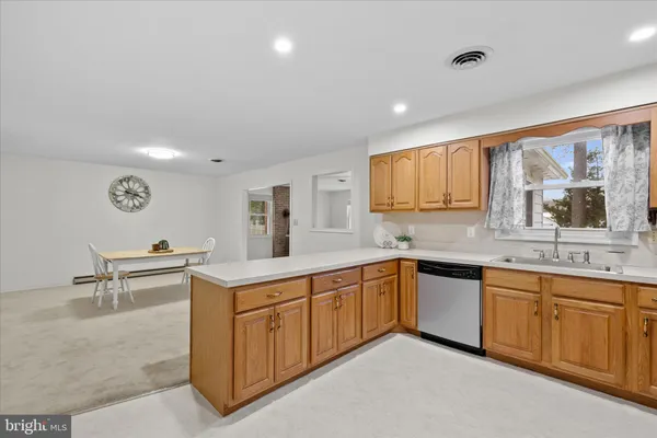 a view of a kitchen counter top space sink stainless steel appliances and window