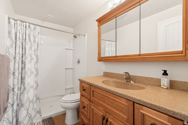 7296 Ridge Road Lake Point, UT 84074 - Photo 36 of 54 Bathroom featuring a wood-finish vanity with a double sink, stone-finish countertop, and a three-door mirrored medicine cabinet