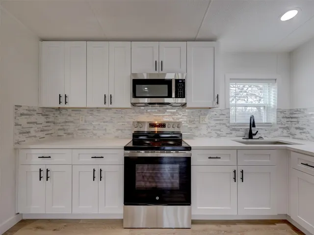 a large kitchen with cabinets wooden floor and stainless steel appliances