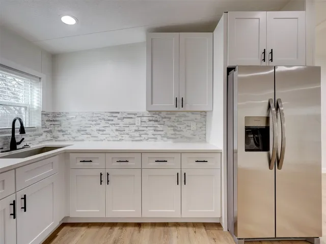 a kitchen with granite countertop white cabinets and stainless steel appliances