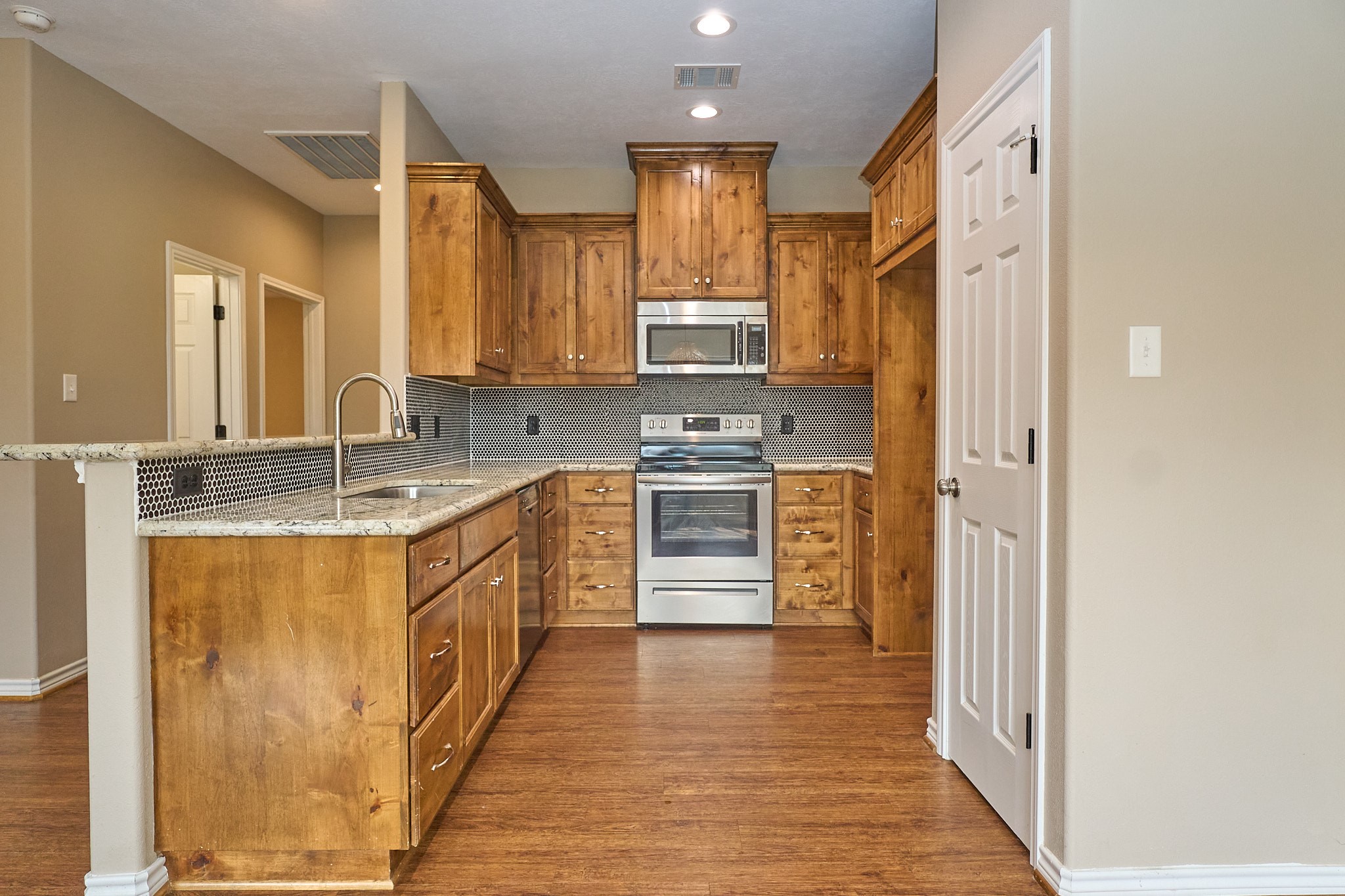 1807 Nuches Lane Bryan, TX 77803 - Photo 9 of 27 This kitchen features warm wood cabinetry, stainless steel appliances, and a stylish backsplash. The granite countertops offer ample workspace, and the open layout is perfect for entertaining.