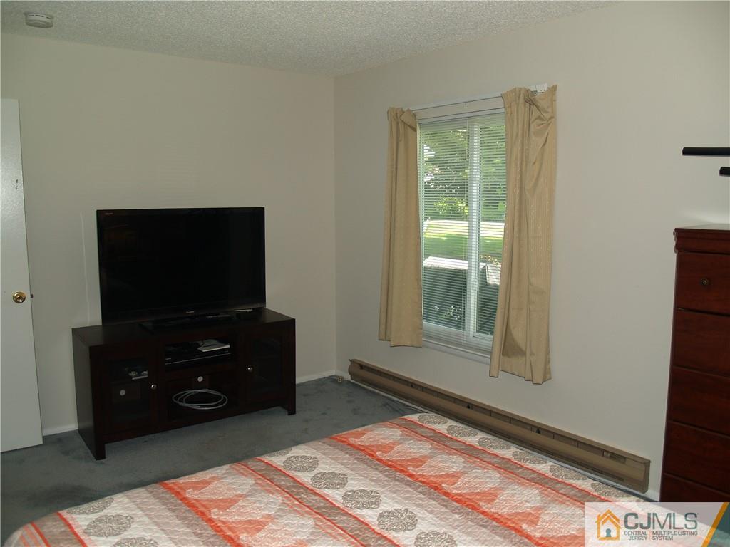 504 A Belford Road, Unit A Monroe Township, NJ 08831 - Photo 36 of 42 a bedroom with a bed and a flat tv screen on a dresser