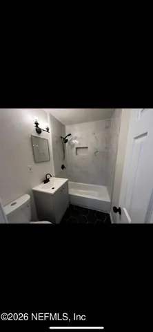 a backyard of a house with plants and large tree