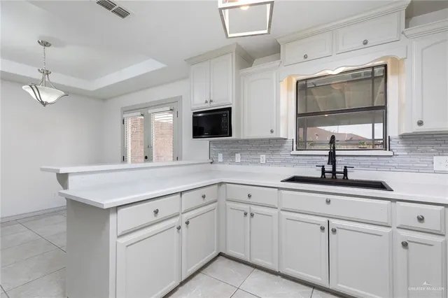 a kitchen with white cabinets appliances and sink