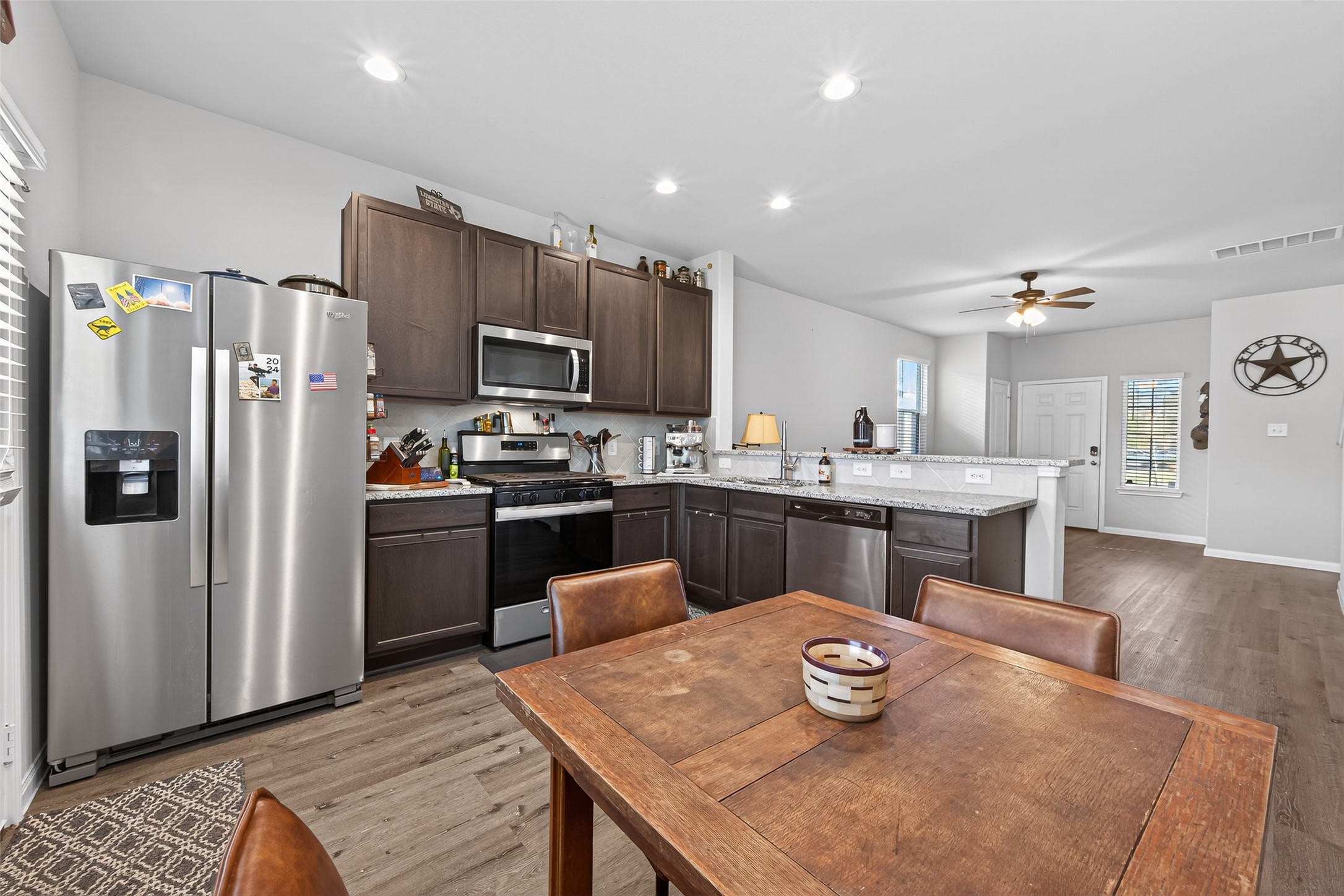 2354 Raider Drive Conroe, TX 77301 - Photo 5 of 20 a kitchen with stainless steel appliances granite countertop a refrigerator a sink a stove a dining table and chairs