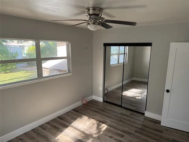 a view of empty room with wooden floor and fan