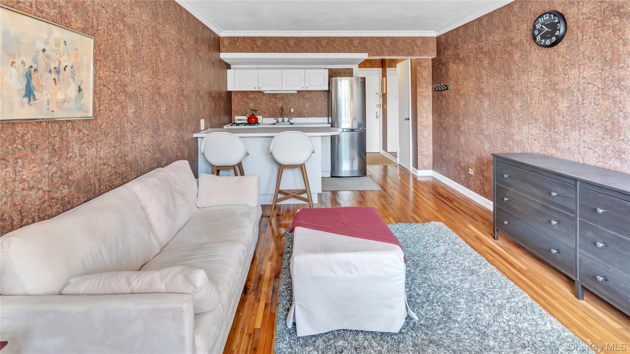 15 Canterbury Road, Unit D18 Great Neck, NY 11021 - Photo 4 of 10 Living area featuring light wood-style flooring, ornamental molding, and wallpapered walls