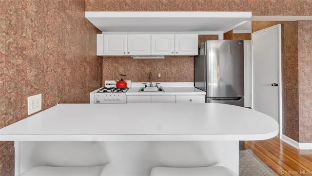 a white kitchen with a refrigerator and a sink