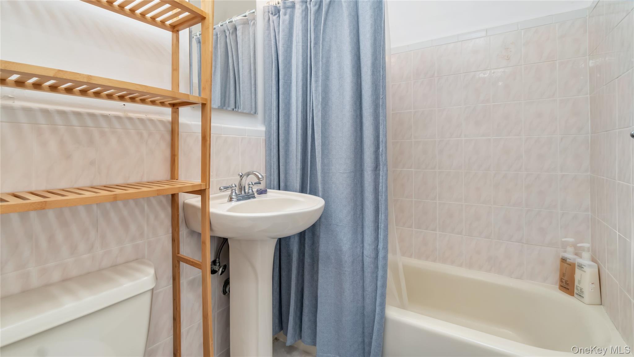 15 Canterbury Road, Unit D18 Great Neck, NY 11021 - Photo 7 of 10 Bathroom featuring tile walls and shower / tub combo with curtain