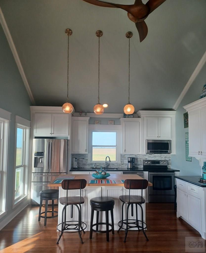 1279 Faggards Road Port Bolivar, TX 77650 - Photo 7 of 16 a kitchen with stainless steel appliances granite countertop a stove top oven a sink a dining table and chairs with wooden floor
