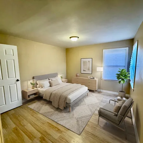 a spacious bedroom with a bed a couch and potted plant