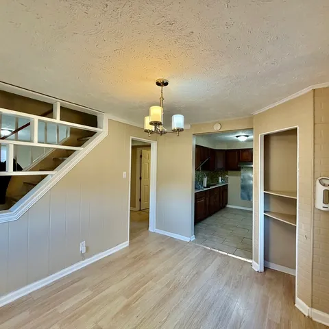 a view of a kitchen with an empty room and wooden floor