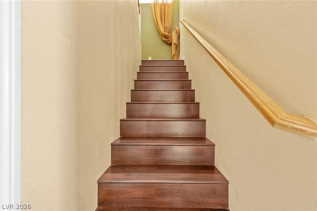 8934 Deep Ridge Court Las Vegas, NV 89178 - Photo 14 of 47 Rich wood steps with a sleek handrail ascend, creating an inviting transition between floors.