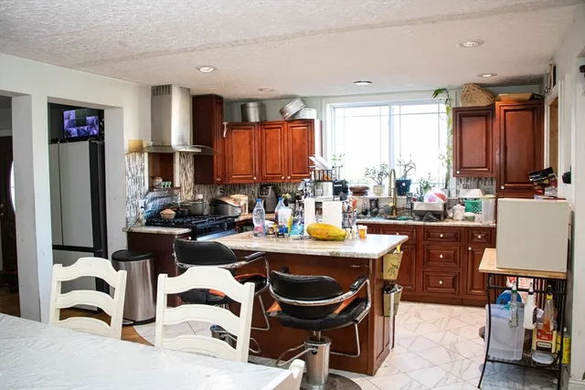 a kitchen with a refrigerator a stove a sink and a dining table with chairs