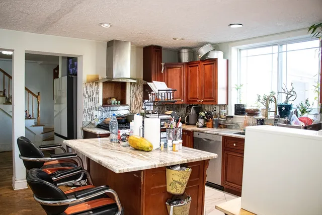a kitchen with a stove a sink a kitchen island with chairs and wooden cabinets