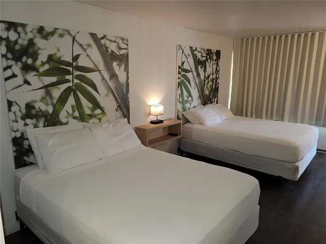 a bedroom with two beds and a painting on the wall