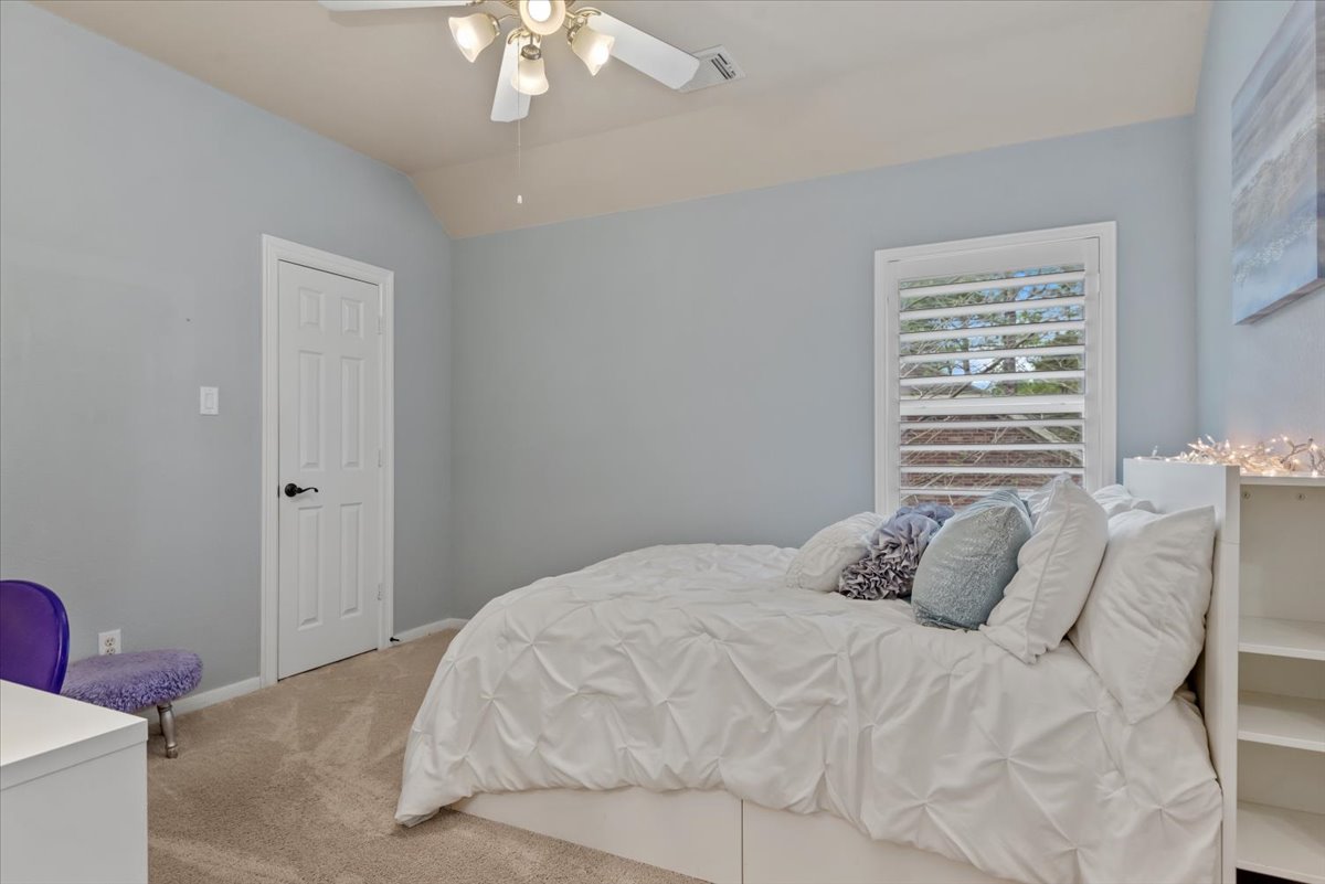 15519 Stallion Point Circle Cypress, TX 77429 - Photo 24 of 37 The room features a vaulted ceiling, a ceiling fan with integrated lighting, and a window with white louvered shutters
