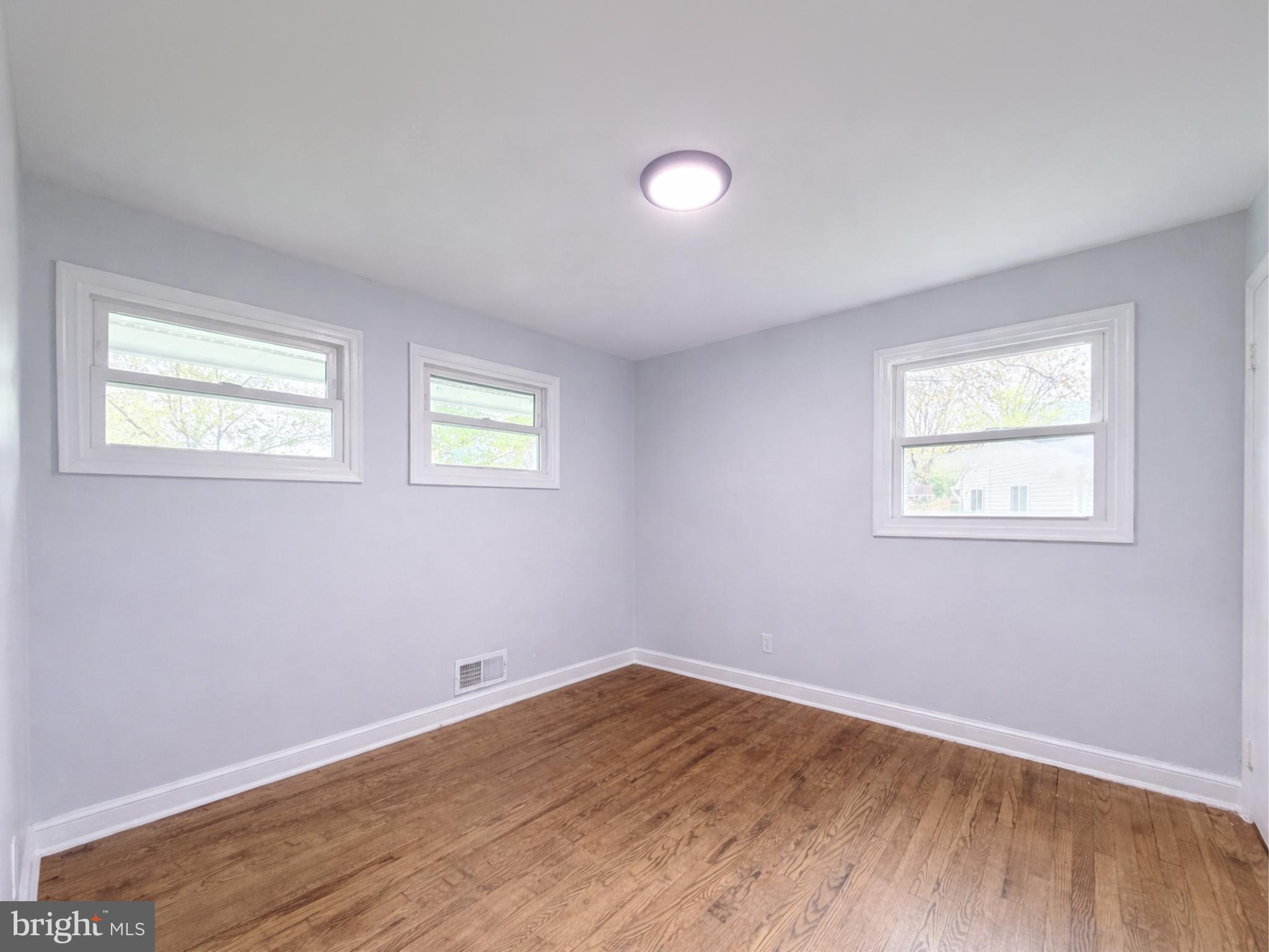 4902 91st Place Lanham, MD 20706 - Photo 22 of 30 a view of an empty room with wooden floor and a window