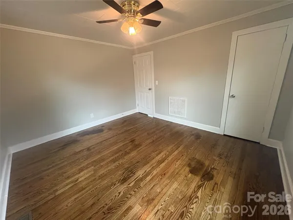 an empty room with wooden floor and fan
