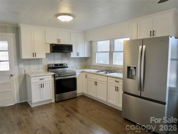 a kitchen with granite countertop a refrigerator stove and sink