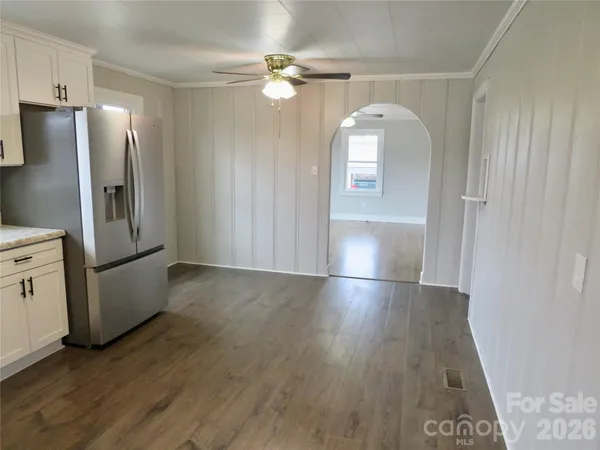 an empty room with wooden floor cabinet and windows