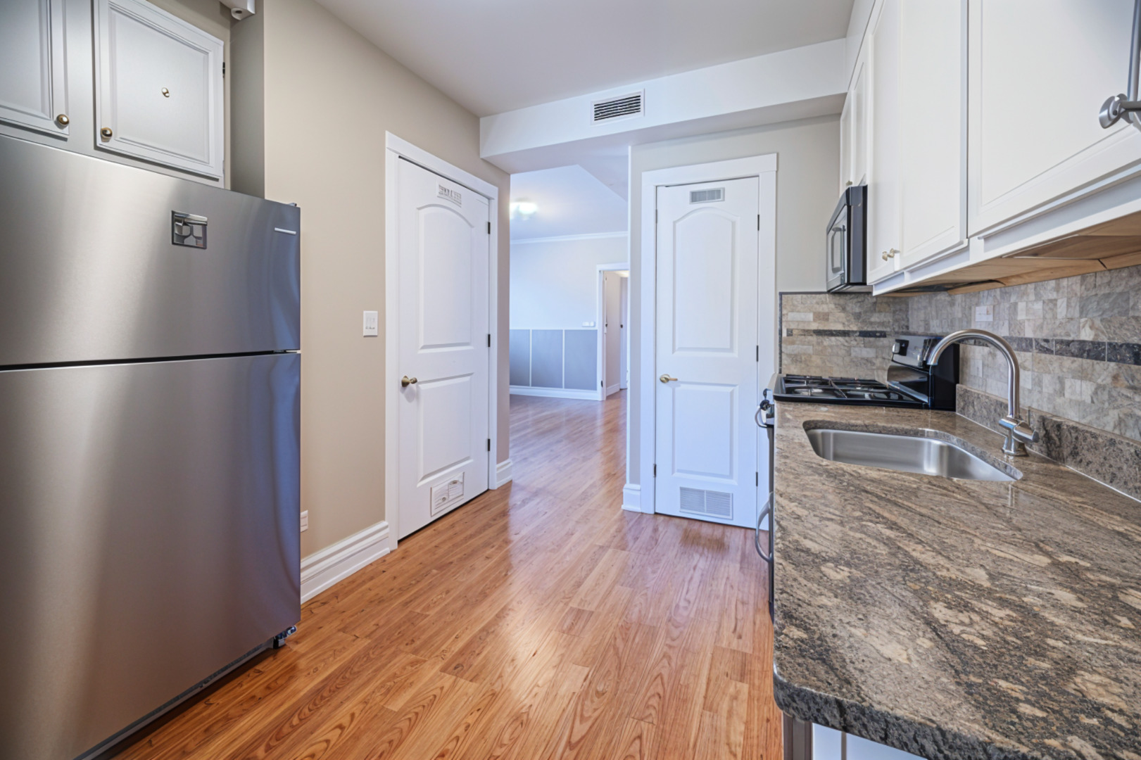 3737 North Pulaski Road, Unit 2S Chicago, IL 60641 - Photo 7 of 33 a kitchen with a refrigerator a stove top oven and wooden floor