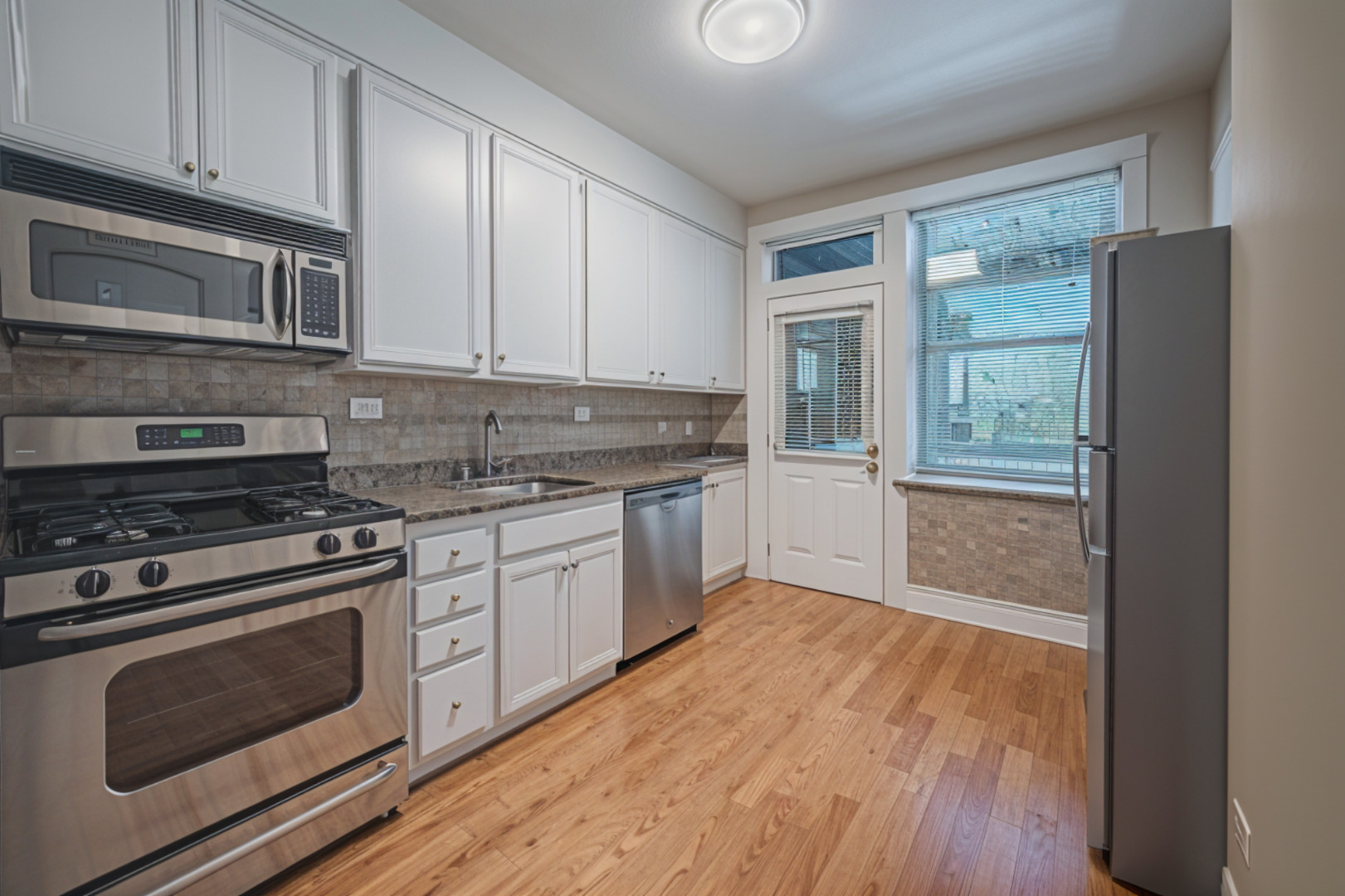 3737 North Pulaski Road, Unit 2S Chicago, IL 60641 - Photo 8 of 33 a kitchen with granite countertop wooden cabinets stainless steel appliances and a window