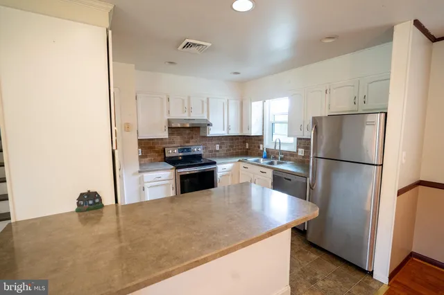 a kitchen with granite countertop a refrigerator a sink a stove a microwave and island