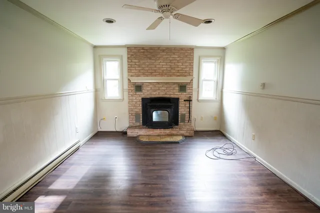 an empty room with wooden floor fireplace and windows
