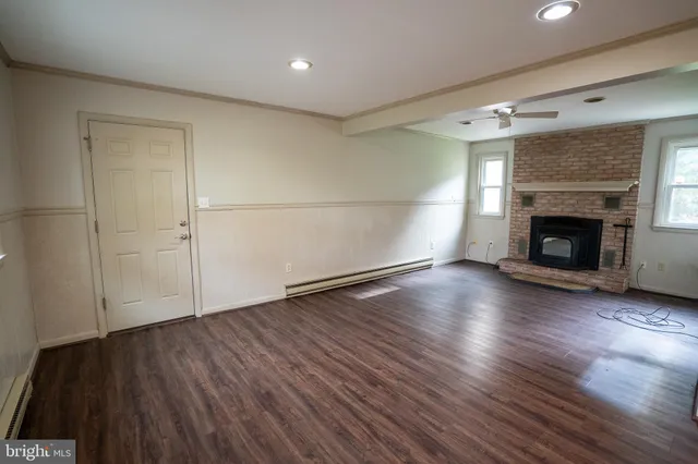 an empty room with wooden floor fireplace and windows