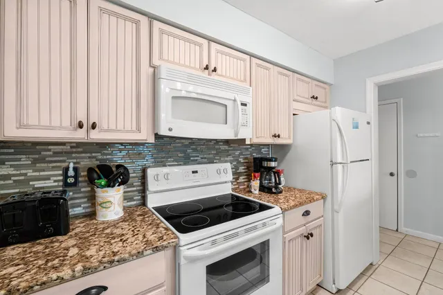 a white refrigerator freezer and a stove sitting inside of a kitchen