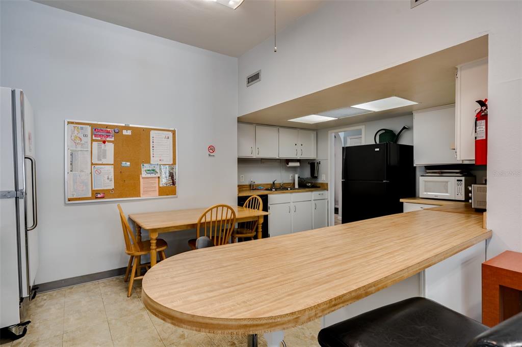 12760 Indian Rocks Road, Unit 546 Largo, FL 33774 - Photo 41 of 45 a kitchen with stainless steel appliances kitchen island granite countertop a refrigerator a stove a sink a dining table and chairs with wooden floor