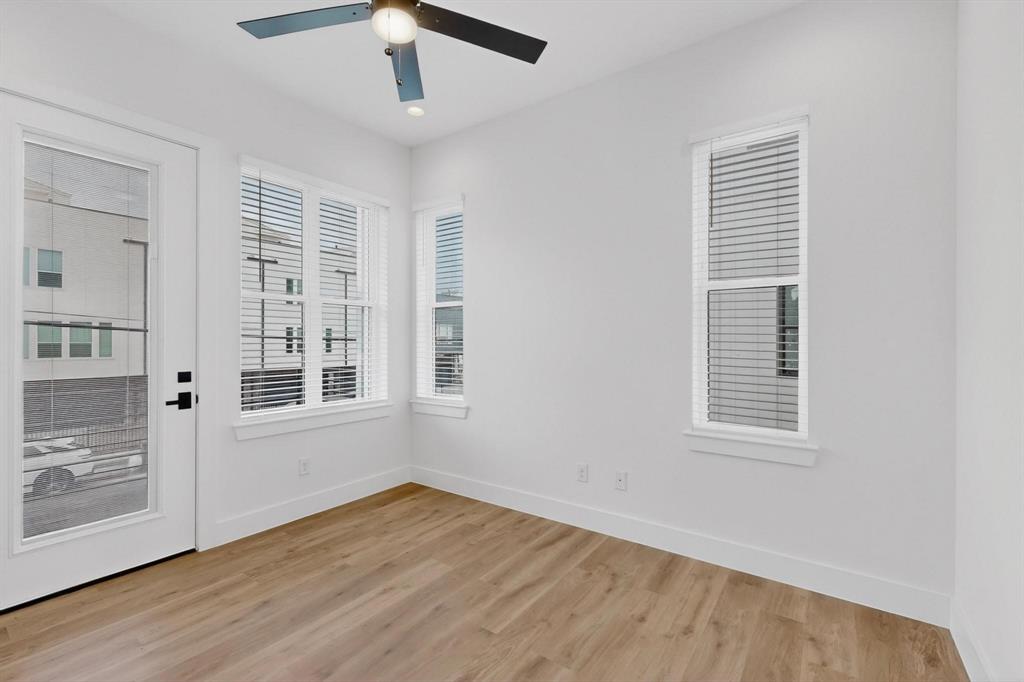 2226 Shea Road, Unit 103 Dallas, TX 75235 - Photo 5 of 35 Spacious room featuring light wood-finish flooring, multiple large windows with blinds, a glass-paneled exterior door, a modern ceiling fan with integrated lighting, and recessed ceiling lights