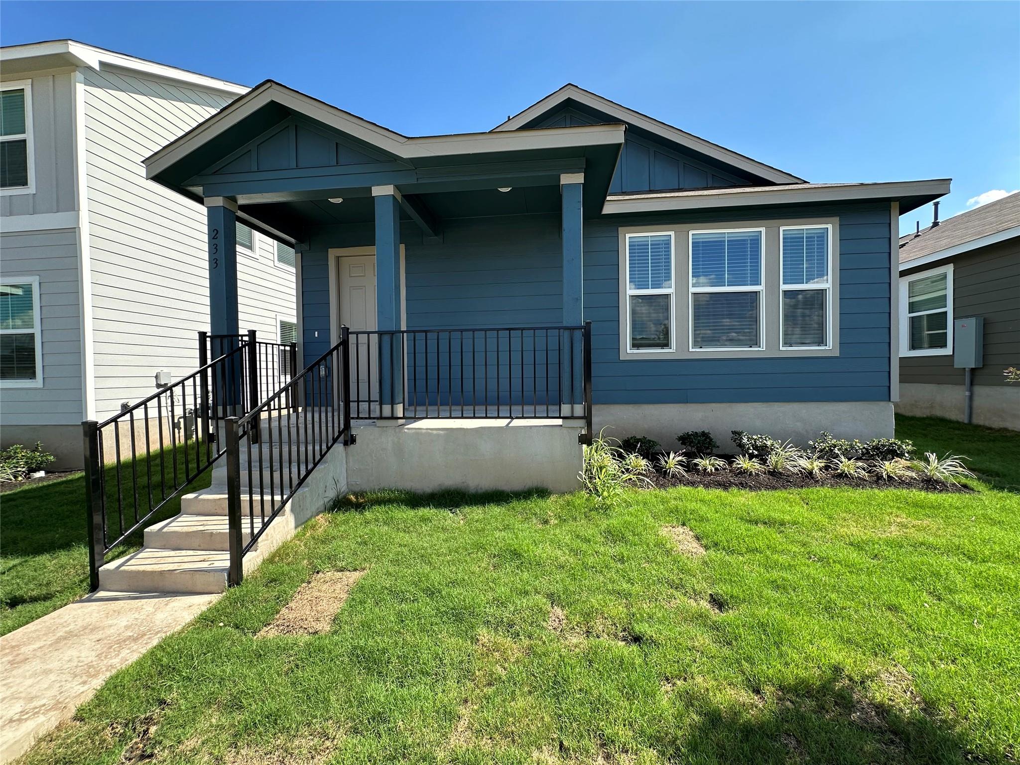 View of front of property with board and batten siding, a front yard, and covered porch