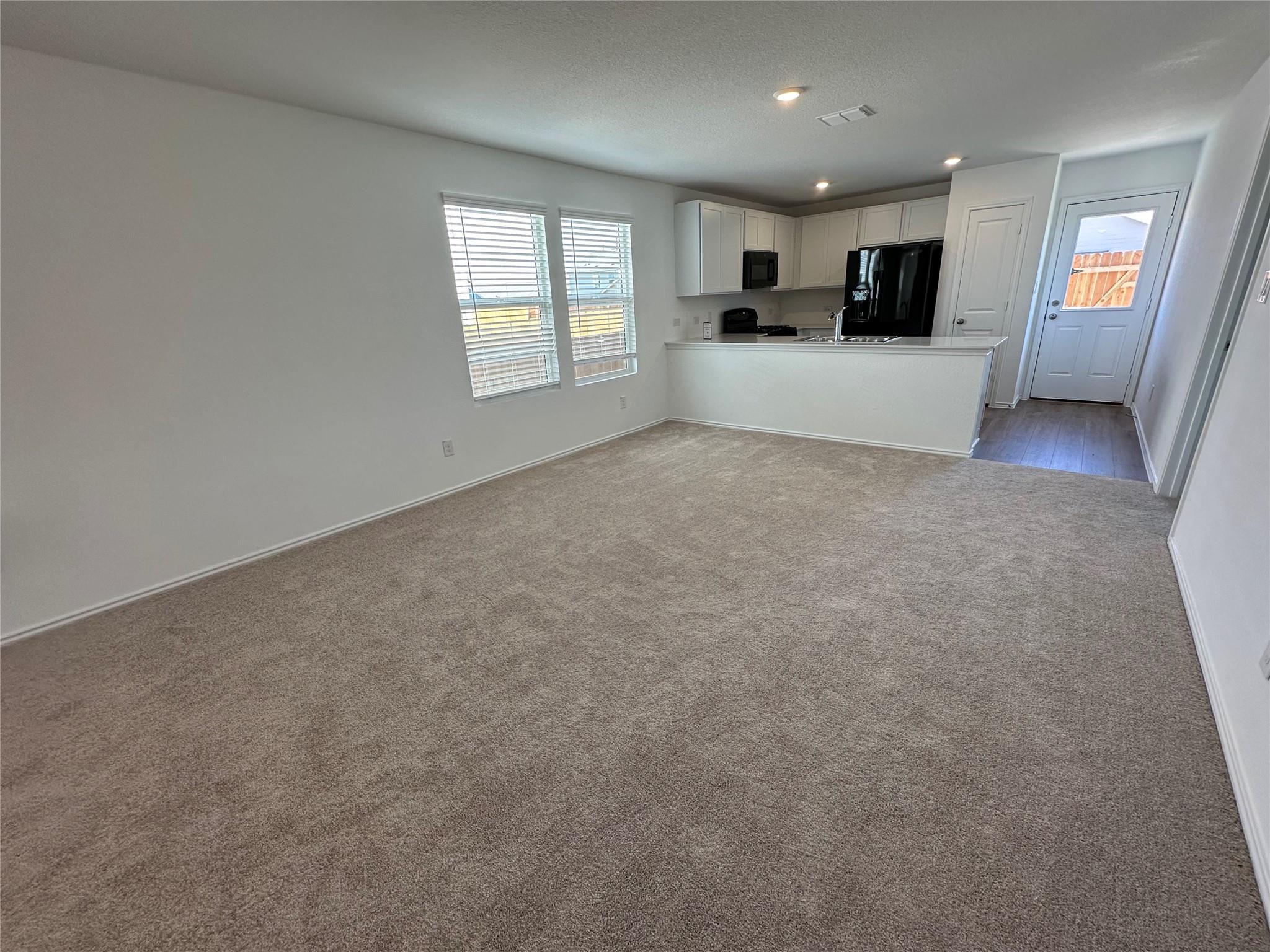233 Magalia Lane Kyle, TX 78640 - Photo 37 of 37 Kitchen with open floor plan, a peninsula, white cabinets, black appliances, and healthy amount of natural light