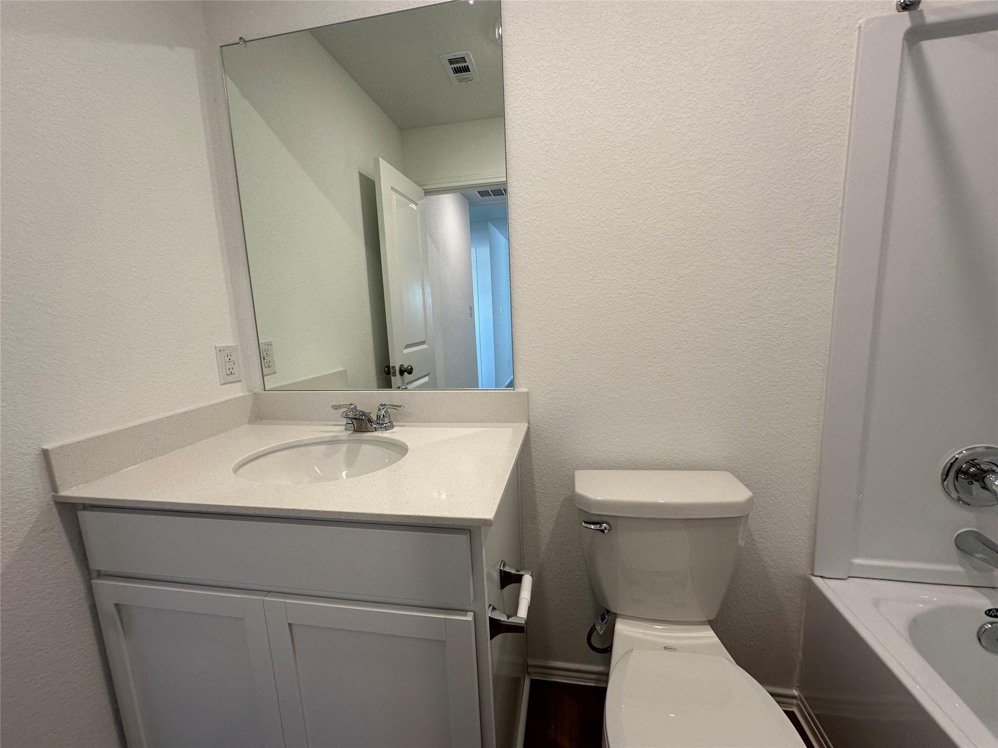 233 Magalia Lane Kyle, TX 78640 - Photo 23 of 37 Full bathroom with a textured wall, vanity, and shower / tub combination