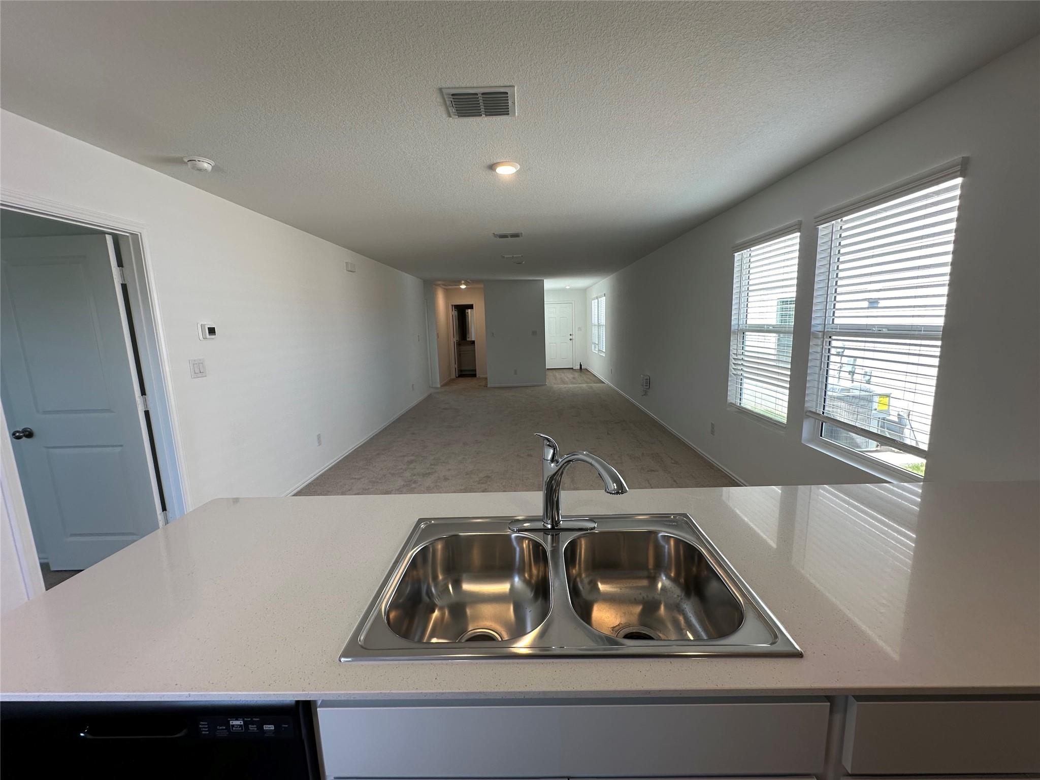 233 Magalia Lane Kyle, TX 78640 - Photo 35 of 37 Kitchen featuring light countertops, carpet, a peninsula, open floor plan, and a textured ceiling