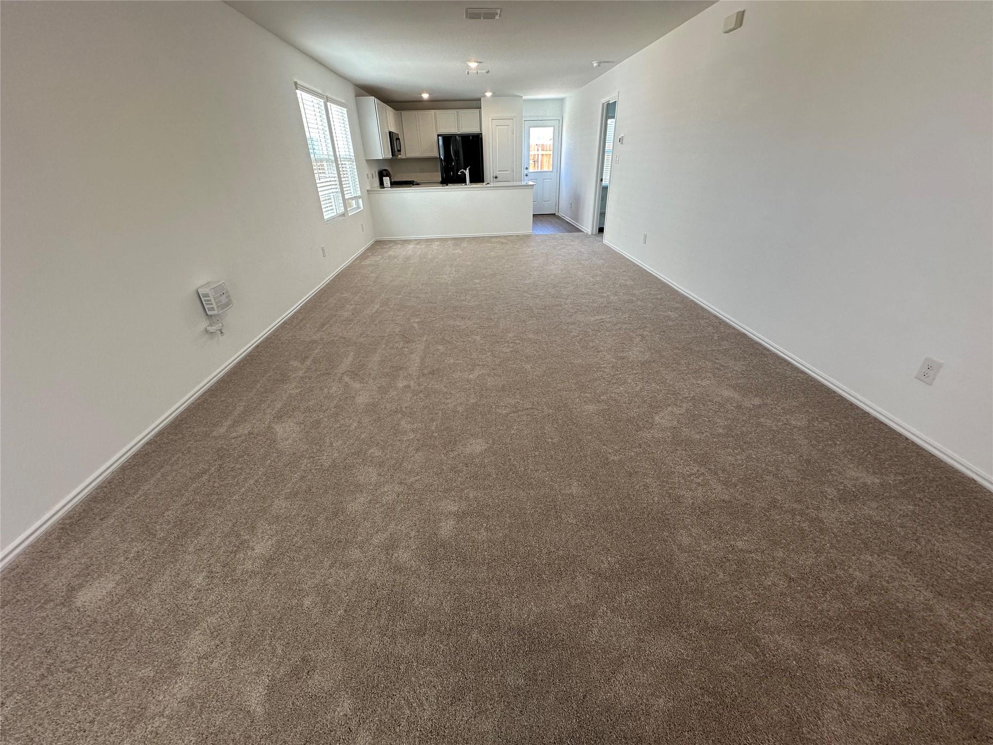 233 Magalia Lane Kyle, TX 78640 - Photo 7 of 37 Unfurnished living room featuring dark carpet and baseboards