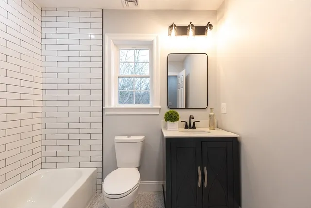 a bathroom with a toilet a sink a mirror a bathtub and window