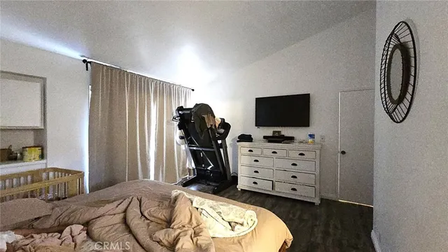 a bedroom with a bed and a flat tv screen on dresser